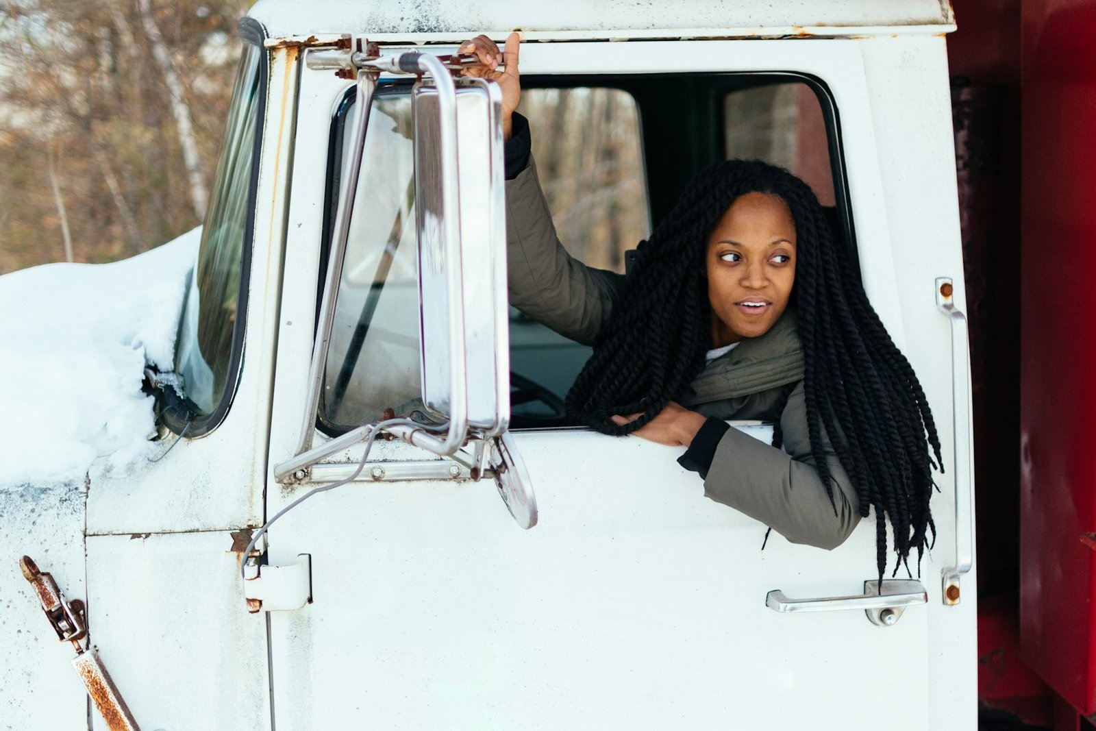 A driver leaning out of a truck cab window on a winter day